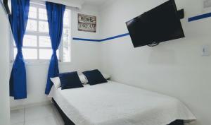 麦德林Casa Hotel Manco Mora的一间卧室配有一张带蓝色窗帘的床和一台平面电视。