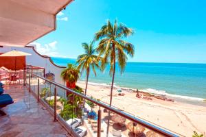巴亚尔塔港Vallarta Shores Beach Hotel的阳台享有棕榈树海滩和大海的景致。