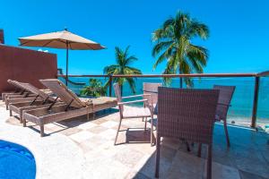 巴亚尔塔港Vallarta Shores Beach Hotel的一个带椅子和遮阳伞的庭院和大海