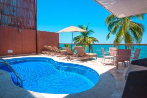 巴亚尔塔港Vallarta Shores Beach Hotel的一个带桌椅的游泳池以及大海