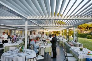 蓬塔阿拉加利亚宫酒店 - 餐厅&酒店的一间设有白色桌子的餐厅,有坐在桌子上的人