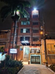 麦德林Hotel Suramericana的一家晚上在酒店前面种植棕榈树的酒店