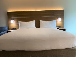 萨默塞特萨默塞特中心快捷假日酒店及套房的一张大白色的床,位于酒店客房内