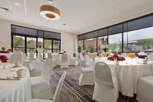 查尔斯顿查尔斯顿西假日酒店及套房的宴会厅配有白色的桌椅和窗户