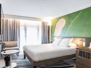 多维尔Novotel Deauville Plage的酒店客房带一张大床和一把椅子