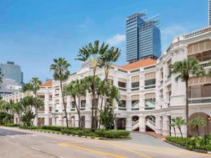新加坡新加坡莱佛士酒店的一条街道前的白色建筑,棕榈树成荫