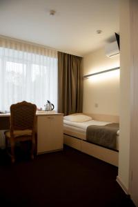 KlintsyUyut Centralnaya Hotel的一间卧室配有一张床、一张书桌和一个窗户。