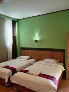 Wonosari纽奥尔琳德斯旅馆的带绿色墙壁的客房内的三张床