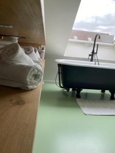 伊普尔Lichtrijke loft bij restaurant Den Olifant的一间带浴缸的浴室,位于窗户旁