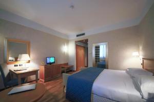 普雷甘纳·米拉内斯莫妮卡费奥拉酒店的酒店客房配有一张床、一张书桌和一台电视。