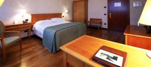 普雷甘纳·米拉内斯莫妮卡费奥拉酒店的配有一张床、一张桌子和一张桌子的酒店客房
