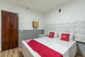 圣保罗OYO Hotel San Remo, São Paulo的卧室配有带红色枕头的大型白色床