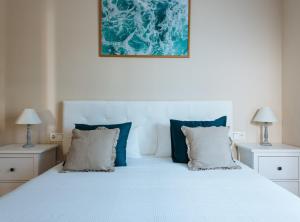塞维利亚Torneo Suite Apartment的一间卧室配有白色床和蓝色枕头