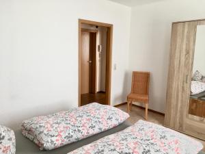 索内贝格Ferienwohnung im Zentrum von Sonneberg的一间设有两张床、椅子和镜子的房间