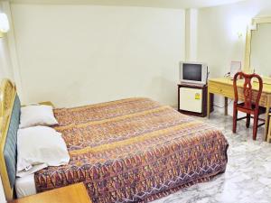 芭堤雅市中心海舞宾馆的一间卧室配有一张床、一张书桌和一台电视