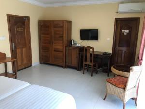西哈努克鲍思高学院酒店的一间卧室配有一张床、一张书桌和一台电视