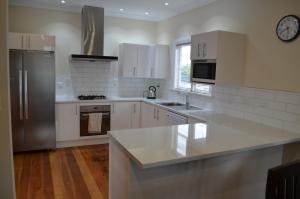 马斯特顿Villa 185- Central Masterton的厨房配有白色橱柜和不锈钢冰箱