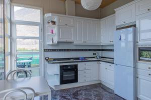 弗龙特拉APARTMENTS ON AN ORGANIC FARM BY THE COAST, Frontera的厨房配有白色橱柜、桌子和窗户。