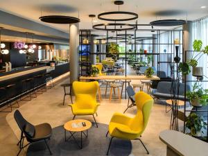 慕尼黑慕尼黑城西宜必思酒店的大堂设有黄色桌椅和酒吧