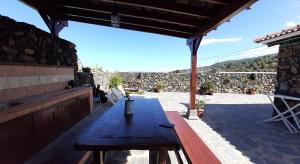 伊科德洛斯维诺斯Casas Rurales Los Guinderos的庭院设有木桌和石墙