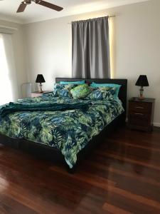 谭伯连山Tamborine Mountain Accommodation的一间卧室配有一张带蓝色和绿色棉被的床