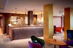 巴德瓦尔特斯多夫Ayurveda Resort MANDIRA的餐厅设有酒吧,配有紫色椅子和桌子