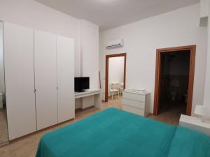 塔兰托All' Ombra del Faro - Mini Apartments的一间卧室配有一张床、一张书桌和一台电视