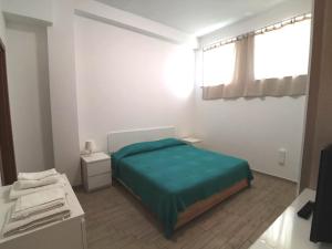 塔兰托All' Ombra del Faro - Mini Apartments的一间卧室设有一张绿色的床和一个窗户。