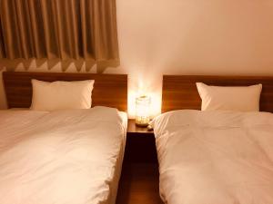 富士河口湖L's Mt.Fuji vacation rental的一间卧室配有两张床,还有一个带时钟的床头柜