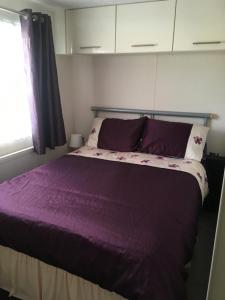 亨伯河畔巴顿Marshlands Lakeside Nature Retreat的一间卧室配有一张带紫色床单的床和窗户。