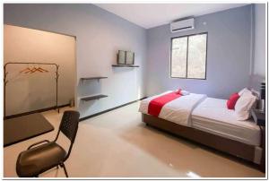DaresRedDoorz Syariah near T2 Juanda Airport 2的一间卧室配有一张床和一把椅子