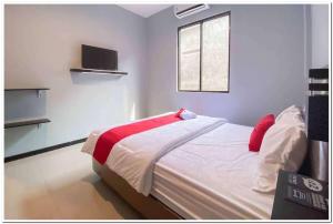 DaresRedDoorz Syariah near T2 Juanda Airport 2的一间卧室配有一张带红色枕头的床和一扇窗户