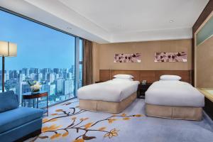 北京北京新云南皇冠假日酒店的带大窗户的客房内的两张床