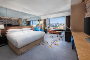 北京北京新云南皇冠假日酒店的一间卧室配有一张大床和一张书桌及电视