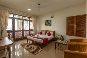 NandiKSTDC Hotel Mayura Pine Top Nandi Hills的一间卧室配有一张床、一张桌子和一张沙发