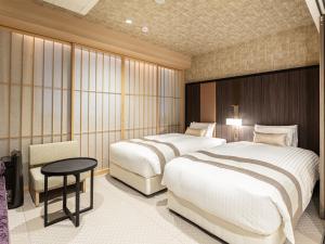 京都Hotel Musse Kyoto Shijo Kawaramachi Meitetsu的酒店客房设有两张床和一张桌子。