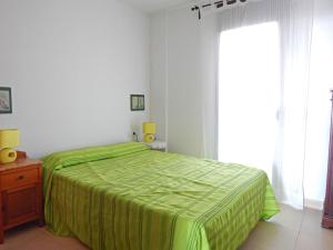 埃斯塔蒂特Apartment La Platja by Interhome的一间卧室设有一张绿色的床和一个窗户。