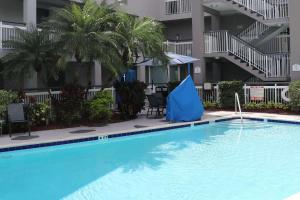 迈阿密Quality Inn Miami Airport - Doral的一座位于酒店的大型游泳池,中间设有一把蓝伞