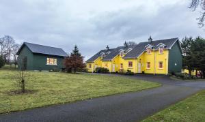 GraiguenamanaghMount Brandon Cottages Graiguenamanagh的黄色的房子,有黑色的屋顶和车道