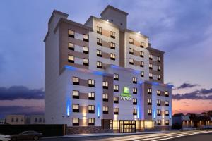 皇后区Holiday Inn Express - Jamaica - JFK AirTrain - NYC, an IHG Hotel的一座白色的大建筑,上面有蓝色的灯光