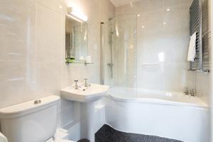特维德上游的贝里克Manor House Hotel Holy Island的白色的浴室设有水槽、卫生间和浴缸。