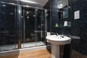 特维德上游的贝里克Manor House Hotel Holy Island的一间带玻璃淋浴和水槽的浴室