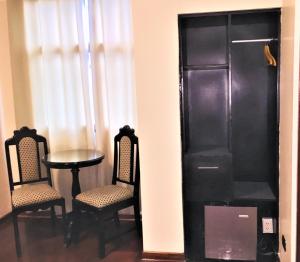 利马Hostal Carlos Tenaud的一间设有桌子和两把椅子以及黑橱柜的房间