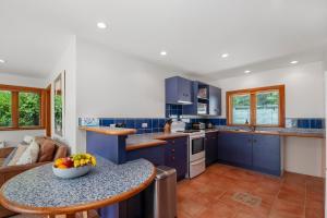 图朗伊Waters Edge Retreat - Motuoapa Holiday Home的厨房配有蓝色橱柜和一碗水果放在桌子上