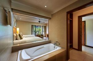 热浪岛塔拉斯海滩Spa度假酒店的带浴缸的浴室和镜子内的一张床铺