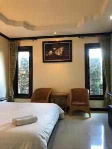色军Siwasom Resort Sakon Nakhon的一间卧室配有一张床、两把椅子和窗户