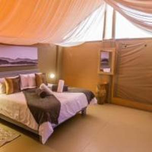 塞斯瑞姆Elegant Desert Camp的一间带床的卧室,位于带窗帘的房间