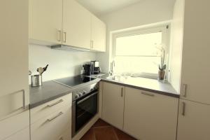 文尼斯塔特Nordseesonne I的厨房配有白色橱柜、水槽和窗户。