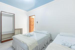 阿拉卡茹Pousada Santa Fé的白色客房的两张床,设有窗户
