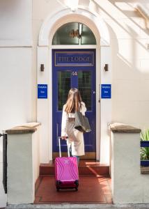 伦敦海豚酒店 - 小屋的一位女士从蓝色的门上拉出一个粉红色的手提箱